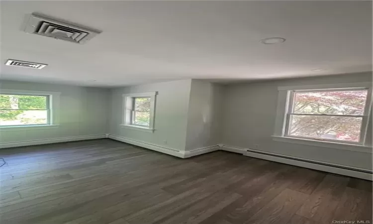 Unfurnished room with a wealth of natural light and dark wood-type flooring