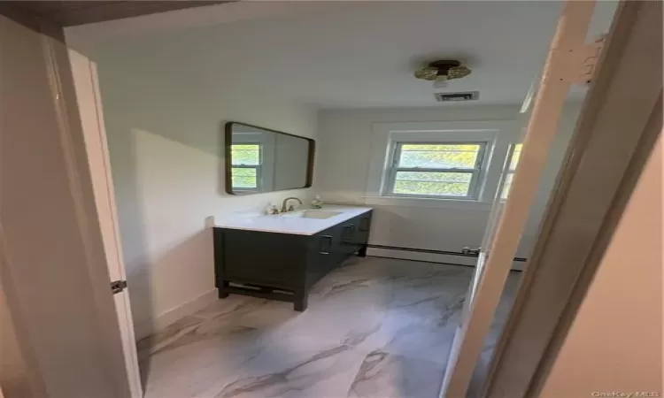 Bathroom featuring tile floors, vanity with extensive cabinet space, and a baseboard radiator