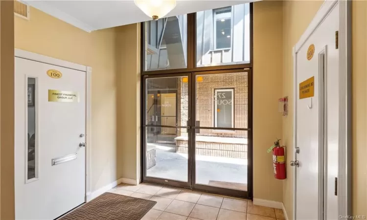 Tiled foyer entrance with crown molding and a wealth of natural light