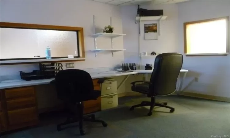 Home office with built in desk, carpet floors, and a drop ceiling