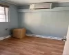 Unfurnished room with a wall mounted air conditioner, crown molding, baseboard heating, and wood-type flooring