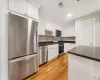 Kitchen featuring stainless steel appliances, light hardwood / wood-style floors, white cabinets, and sink