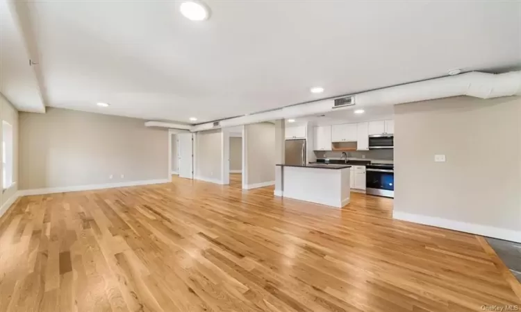 Unfurnished living room featuring sink and light wood-type flooring