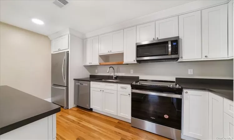 Kitchen featuring white cabinetry, stainless steel appliances, light hardwood / wood-style floors, and sink