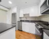 Kitchen with appliances with stainless steel finishes, white cabinetry, sink, and light wood-type flooring