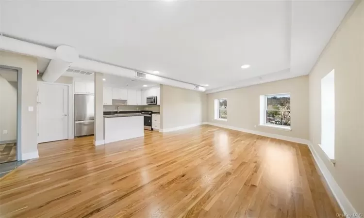 Unfurnished living room with sink and light wood-type flooring