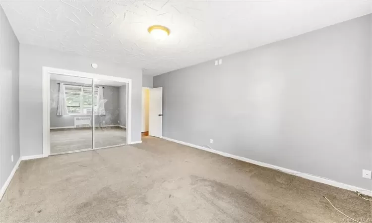 Unfurnished bedroom featuring a textured ceiling, a closet, and carpet floors