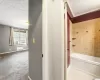 Bathroom featuring tile flooring, tiled shower / bath combo, a textured ceiling, ornamental molding, and radiator heating unit