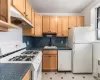 Kitchen featuring radiator, white appliances, backsplash, sink, and light tile floors