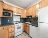 Kitchen with white appliances, sink, tasteful backsplash, and light tile floors