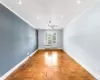 Empty room featuring radiator, ornamental molding, ceiling fan, and light parquet flooring