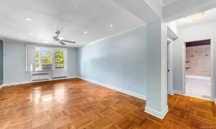 Empty room with parquet floors, ceiling fan, and radiator