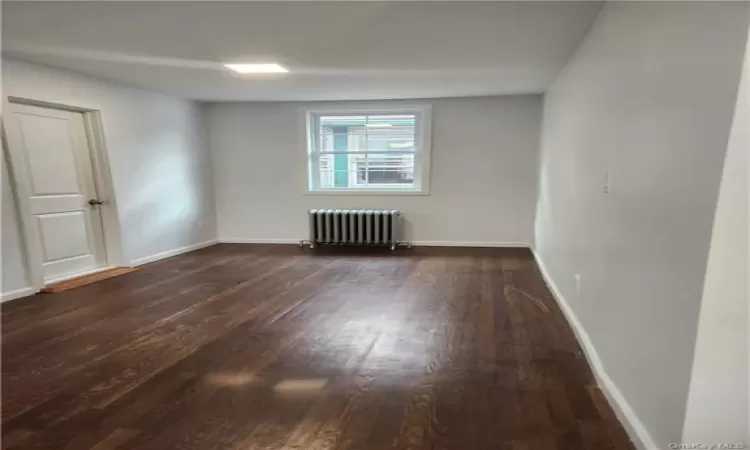 Spare room with hardwood / wood-style flooring and radiator heating unit