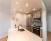 Kitchen featuring light wood-type flooring, light stone counters, backsplash, sink, and appliances with stainless steel finishes