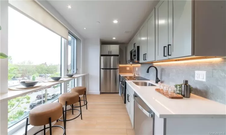 Kitchen featuring a wealth of natural light, appliances with stainless steel finishes, tasteful backsplash, and light hardwood / wood-style floors