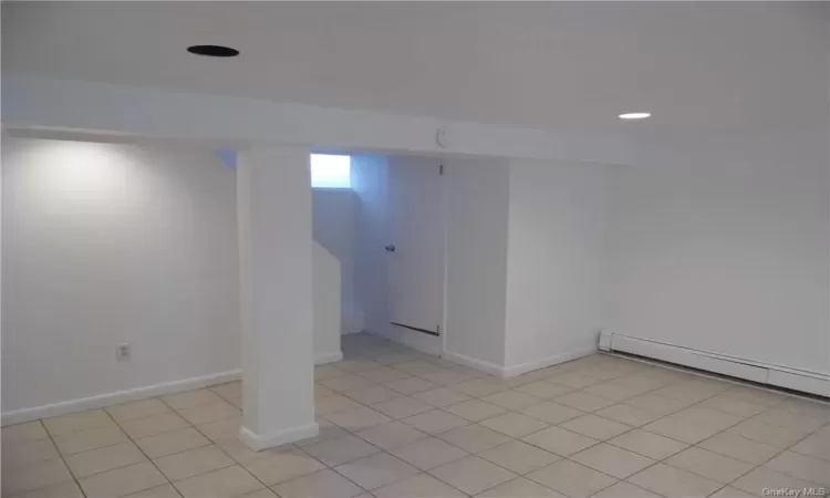 Basement with a baseboard radiator and light tile floors