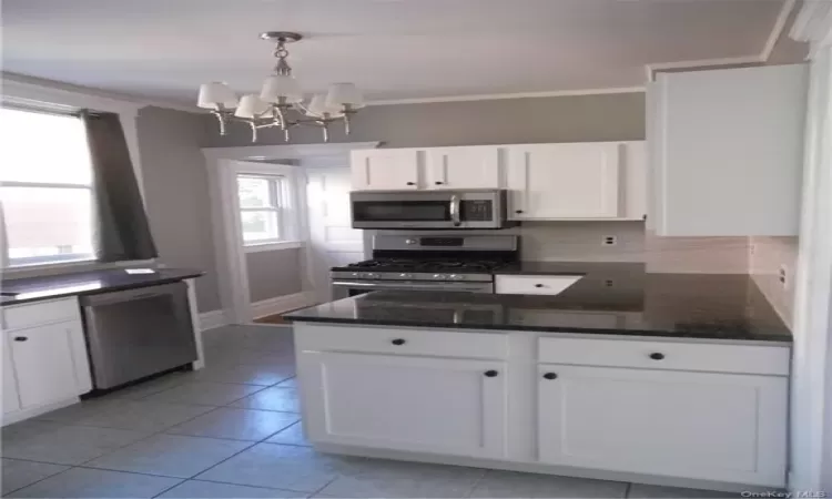 Kitchen with a chandelier, dishwasher, tasteful backsplash, white cabinetry, and gas stove