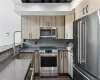 Kitchen with appliances with stainless steel finishes, sink, tasteful backsplash, and dark wood-type flooring