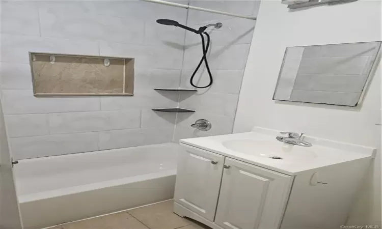 Bathroom featuring vanity, tile patterned flooring, and tiled shower / bath combo