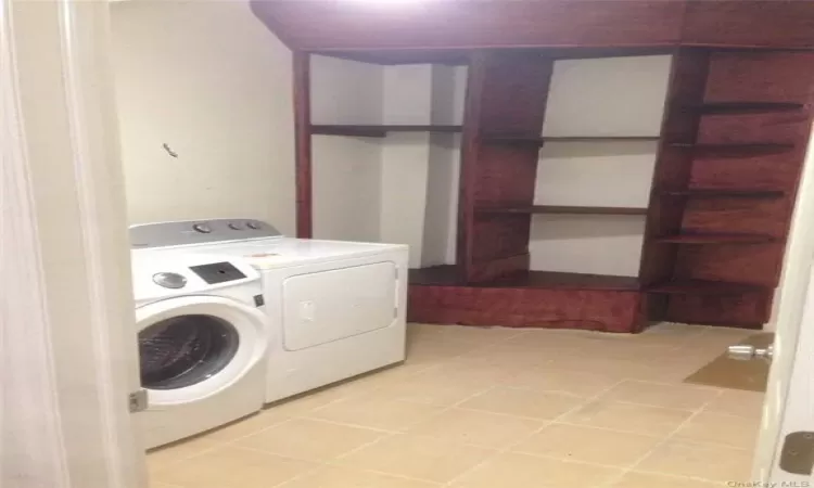 Clothes washing area featuring light tile flooring and washing machine and clothes dryer