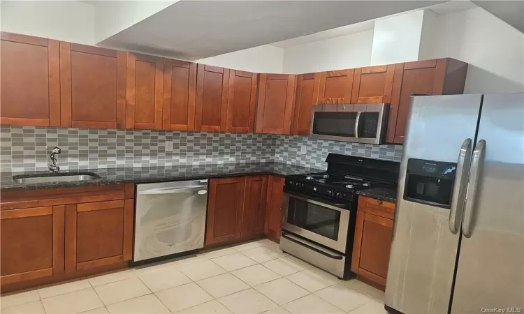 Kitchen with stainless steel appliances, tasteful backsplash, and light tile patterned floors