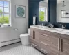 Bathroom featuring dual bowl vanity, tile flooring, baseboard heating, and toilet