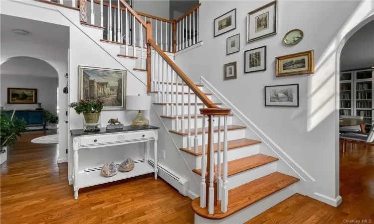 Staircase with wood-type flooring and a baseboard heating unit