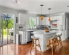 Kitchen featuring dishwasher, hanging light fixtures, a center island, white cabinets, and hardwood / wood-style flooring