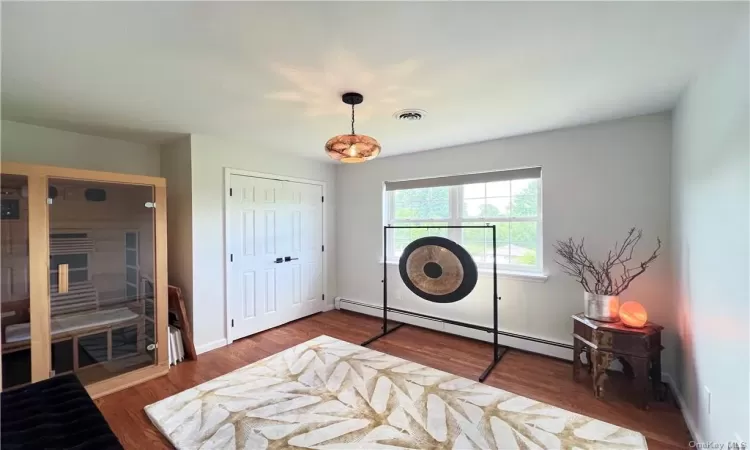 Bedroom featuring baseboard heating, a closet, and hardwood / wood-style flooring