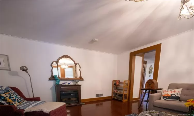 Living room with dark wood-type flooring and crown molding