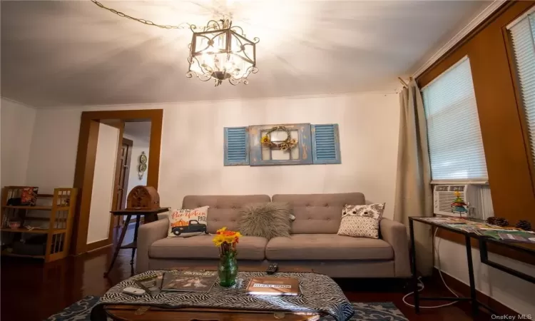 Living room with dark hardwood / wood-style floors and an inviting chandelier