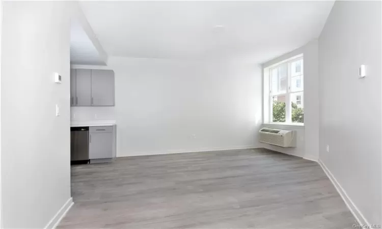 Unfurnished living room featuring a wall mounted AC and light wood-type flooring