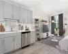 Kitchen with dishwasher, gray cabinetry, sink, and light hardwood / wood-style floors