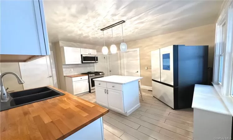 Kitchen featuring stainless steel appliances, white cabinetry, a center island, and tasteful backsplash