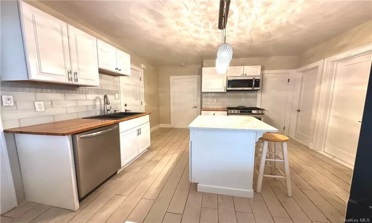 Kitchen with a center island, white cabinetry, sink, and stainless steel appliances