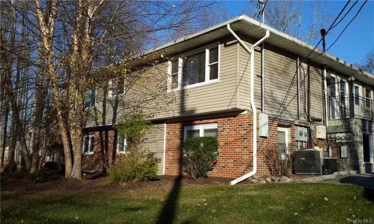 View of side of property with central AC unit and a yard