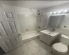 Full bathroom with tile floors, tiled shower / bath, toilet, and vanity