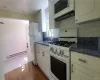 Kitchen featuring a baseboard heating unit, white appliances, dark hardwood / wood-style floors, sink, and tasteful backsplash