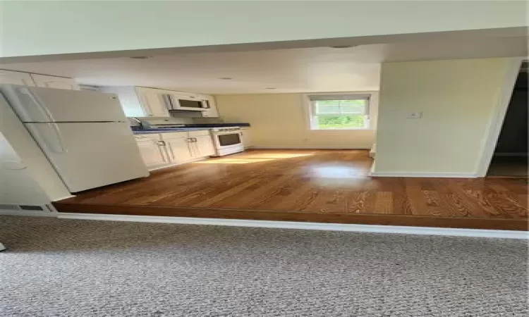 Kitchen with white cabinets, range, fridge, and hardwood / wood-style floors