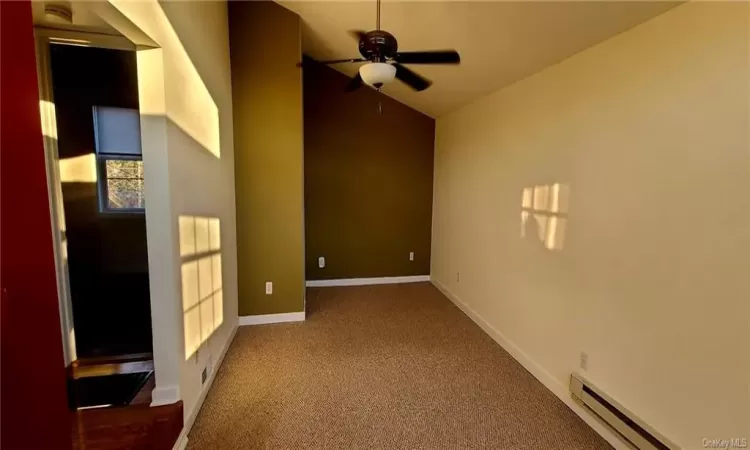 Carpeted empty room featuring ceiling fan and baseboard heating