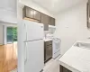 Kitchen with dark brown cabinetry, sink, light hardwood / wood-style flooring, and white appliances