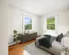 Virtually staged. Bedroom featuring a baseboard heating unit, a textured ceiling, and light wood-type flooring