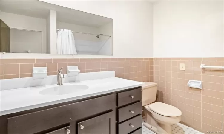 Bathroom featuring tile walls, backsplash, oversized vanity, toilet, and tile floors