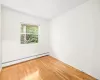 Empty room featuring light hardwood / wood-style floors and a baseboard heating unit