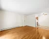 Empty room with a baseboard heating unit, light hardwood / wood-style floors, and ceiling fan