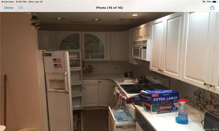 Kitchen featuring white cabinets, dark hardwood / wood-style flooring, and white appliances