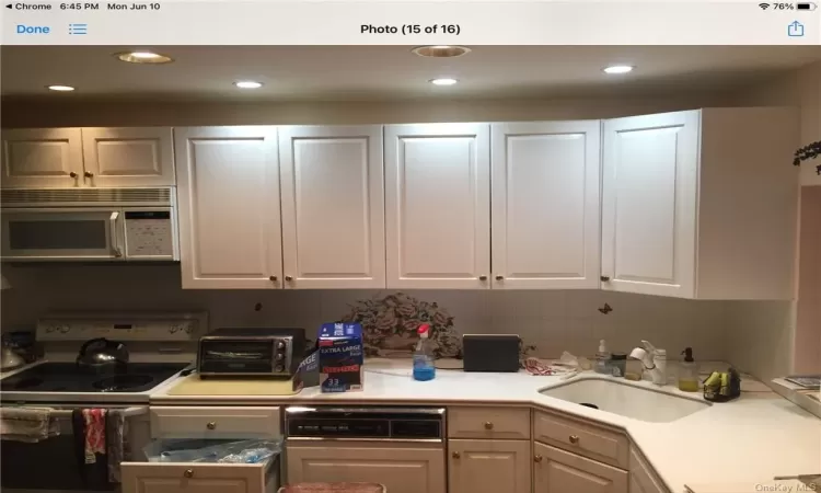 Kitchen with sink, white cabinetry, electric stove, and tasteful backsplash