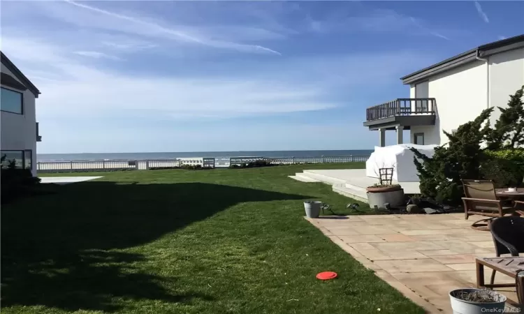 View of yard featuring a patio, a water view, and a balcony