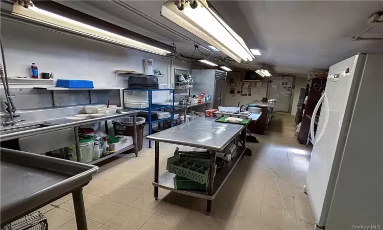 Kitchen with tile floors, stainless steel counters, and white refrigerator