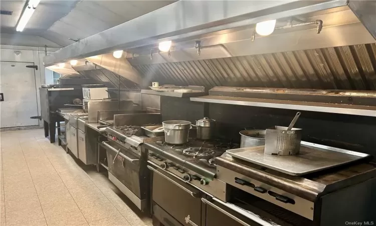 Kitchen featuring light tile floors, lofted ceiling and ansul fire supression system.Burners, ovens ++++++